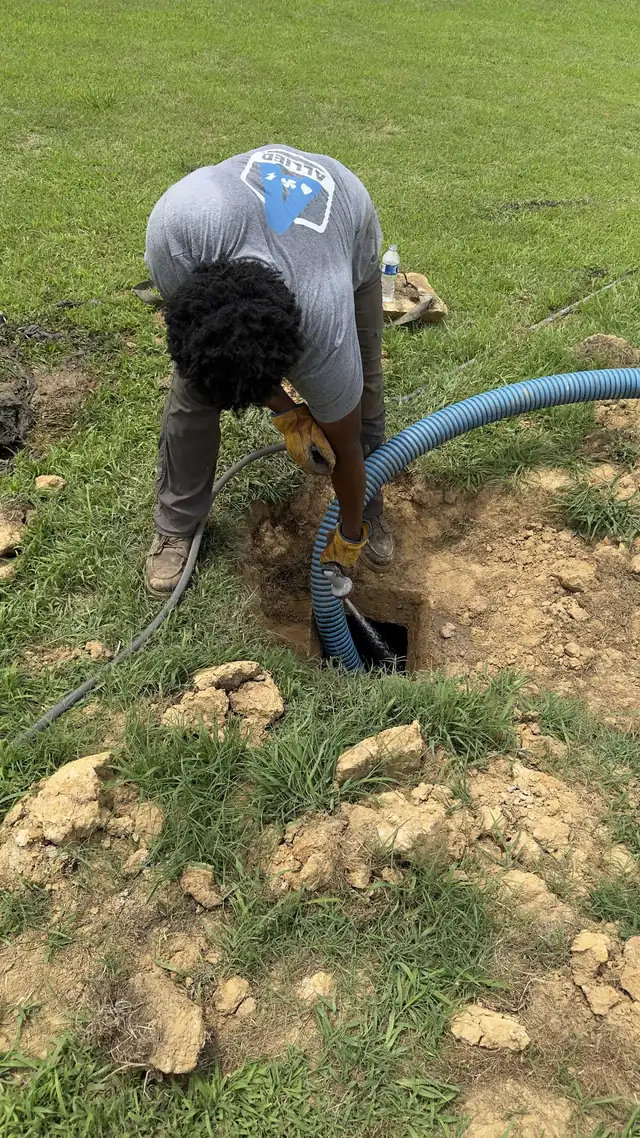 An Allied technician pumping out an open septic tank on a residential lawn